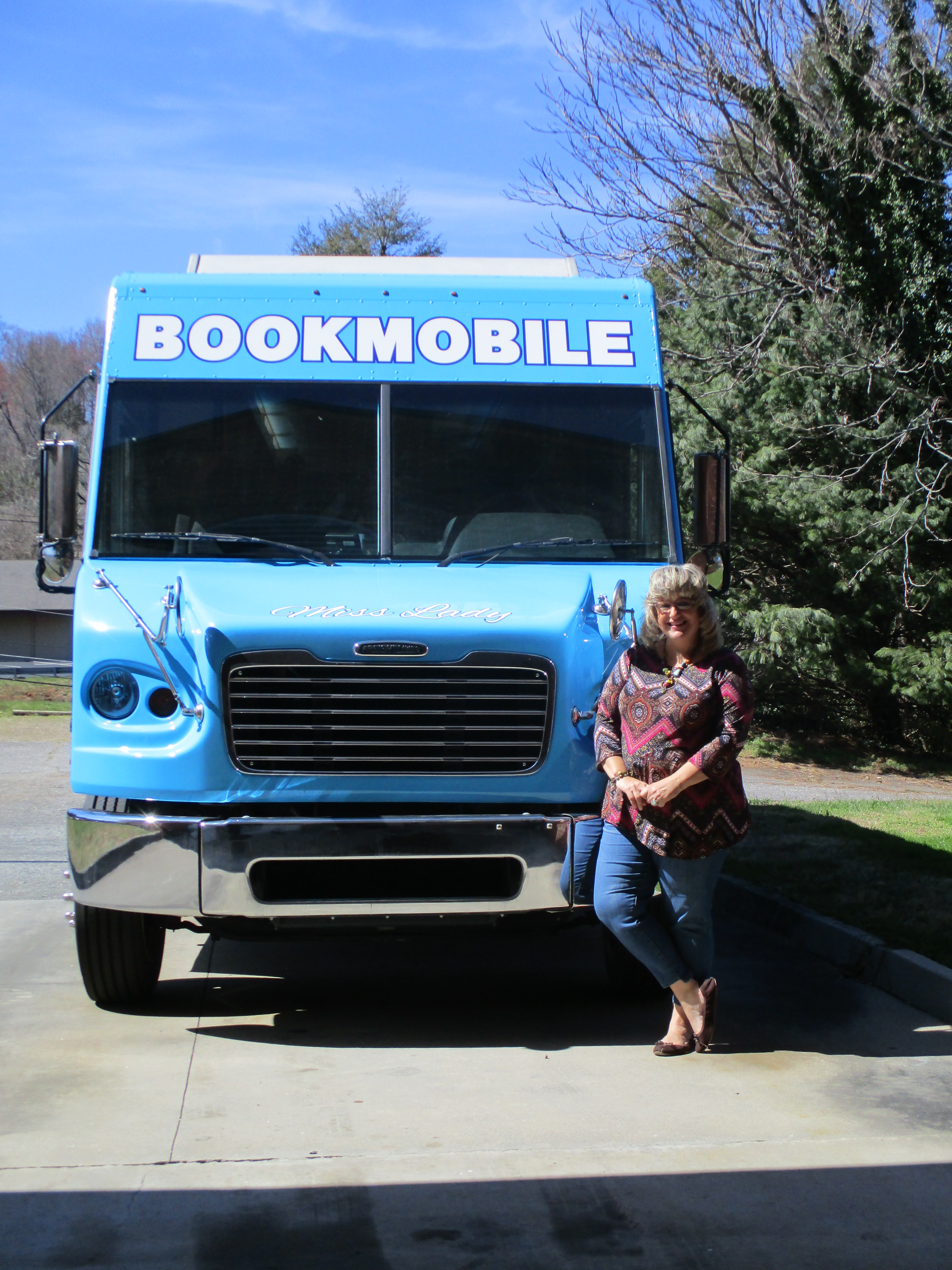 bookmobile driver tammy cope standing with the bookmobile front profile